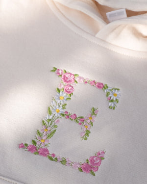 Uppercase E embroidered using floral design in pastel pink